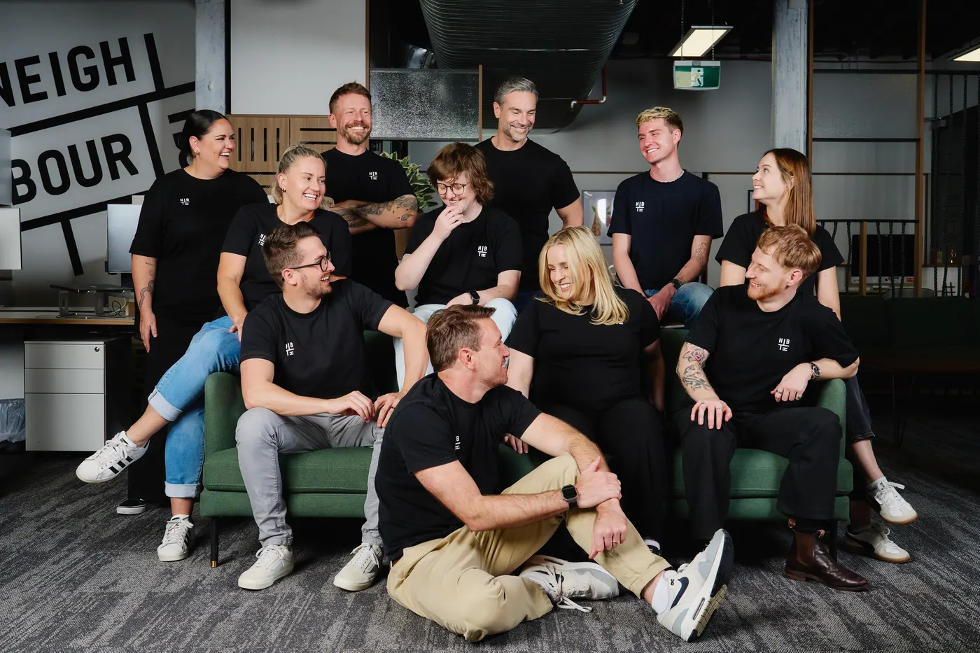 The Neighbourhood crew together on the couch at the Teneriffe office, most of them laughing