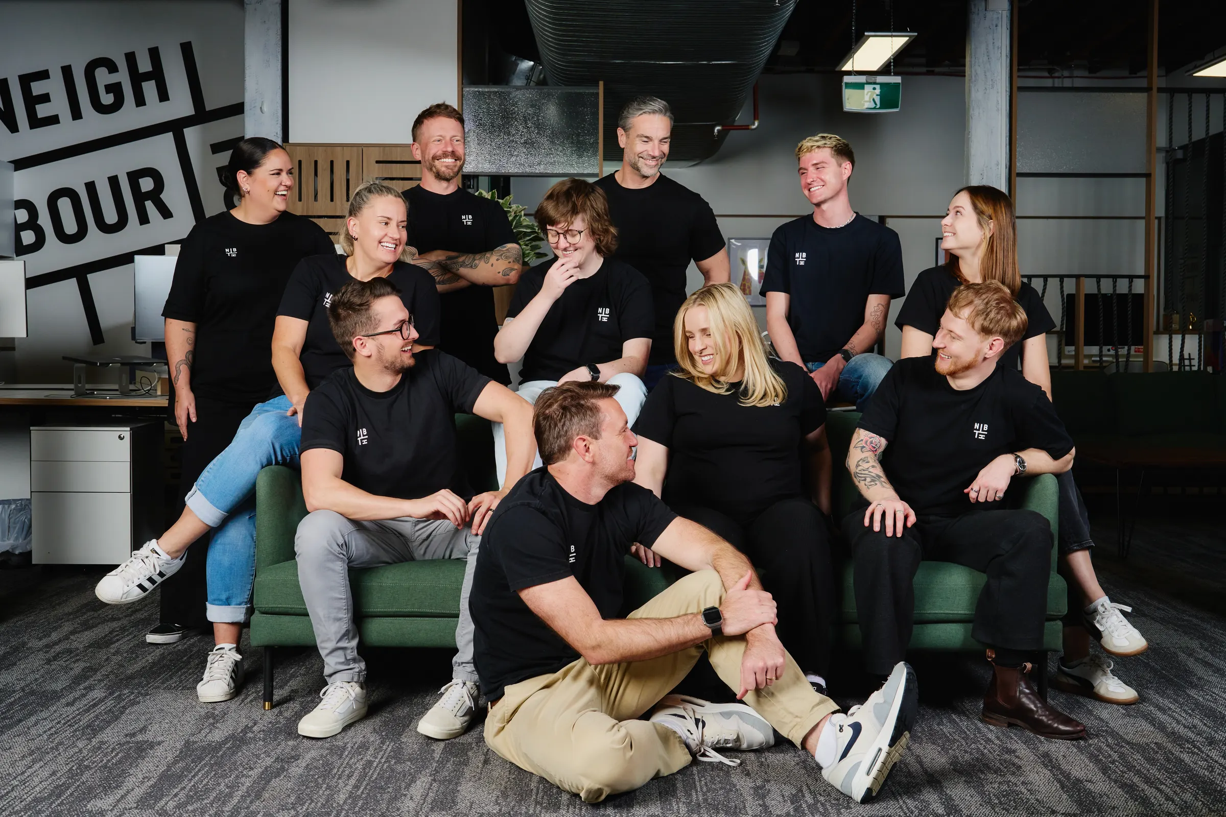 The Neighbourhood crew together on the couch at the Teneriffe office, most of them laughing