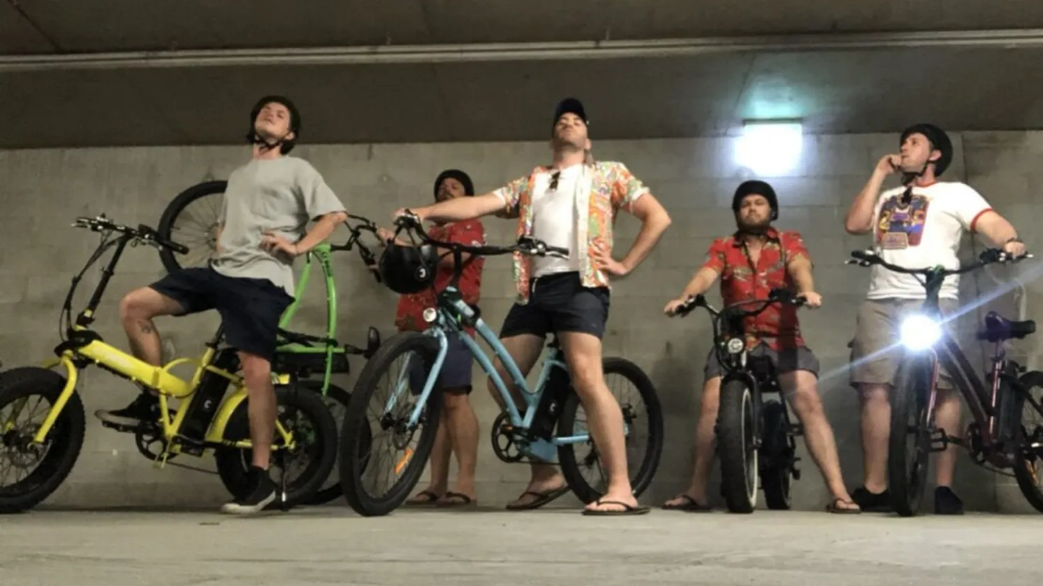 Five of the crew posing on e-bikes in a carpark at night