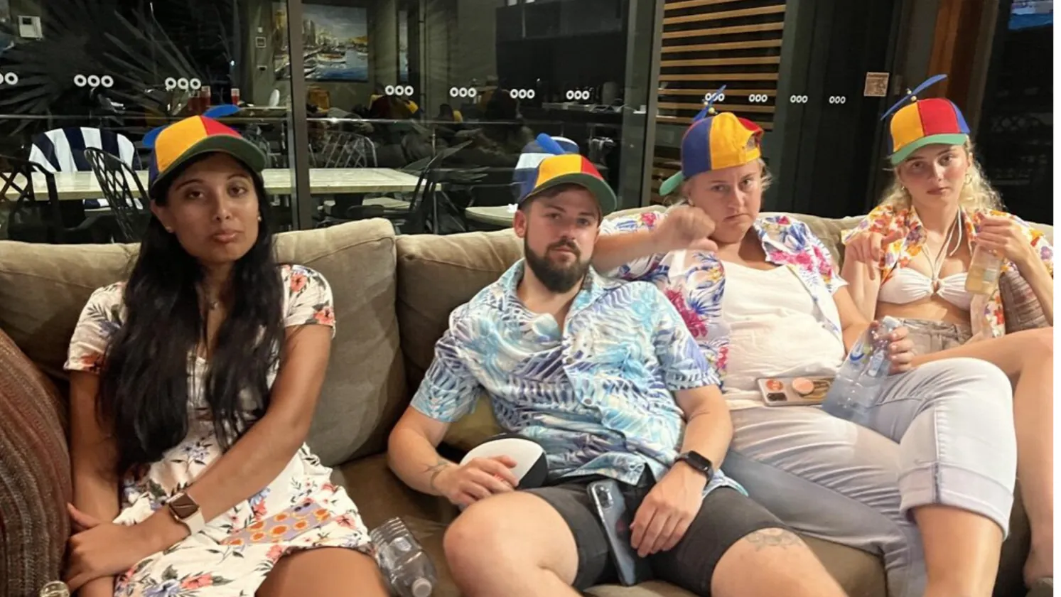 Four of the crew slumped on a couch in Hawaiian shirts and propeller caps