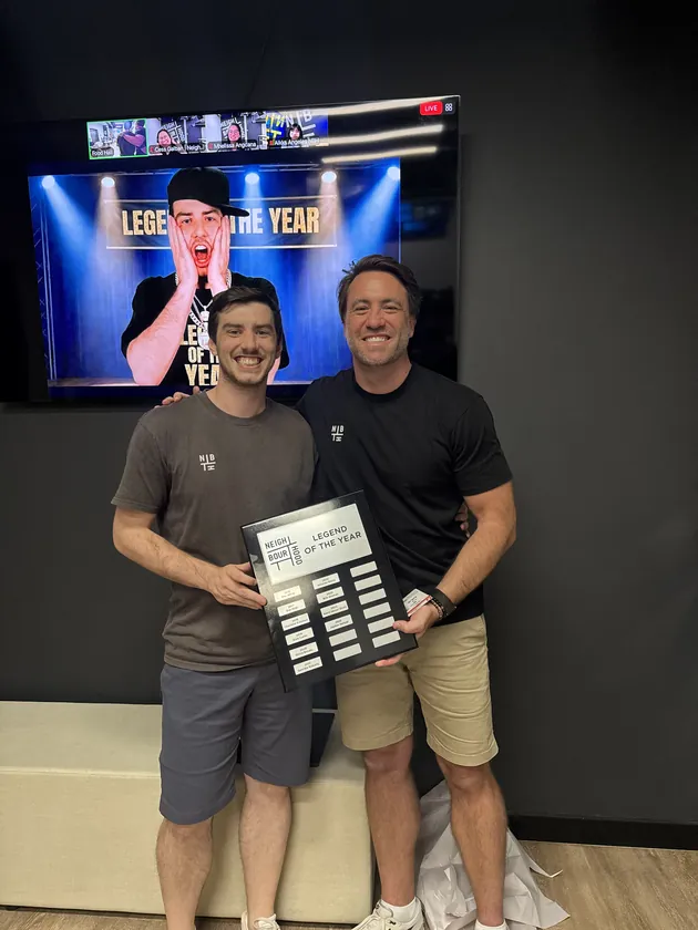 Two of the crew holding the Legend of the Year honour board in front of a screen reading Legend of the Year