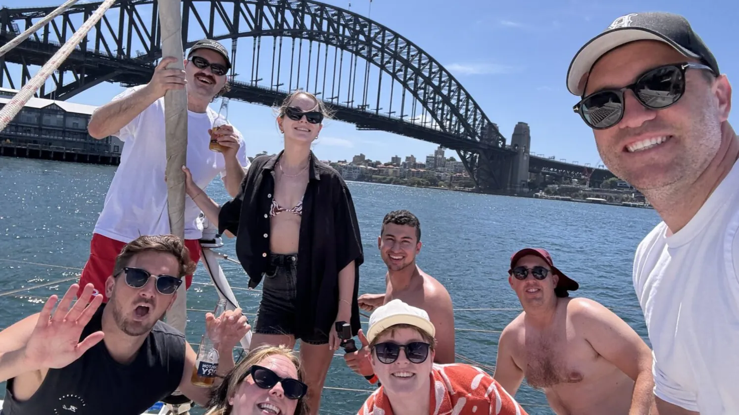 The crew on a yacht in front of the Sydney Harbour Bridge