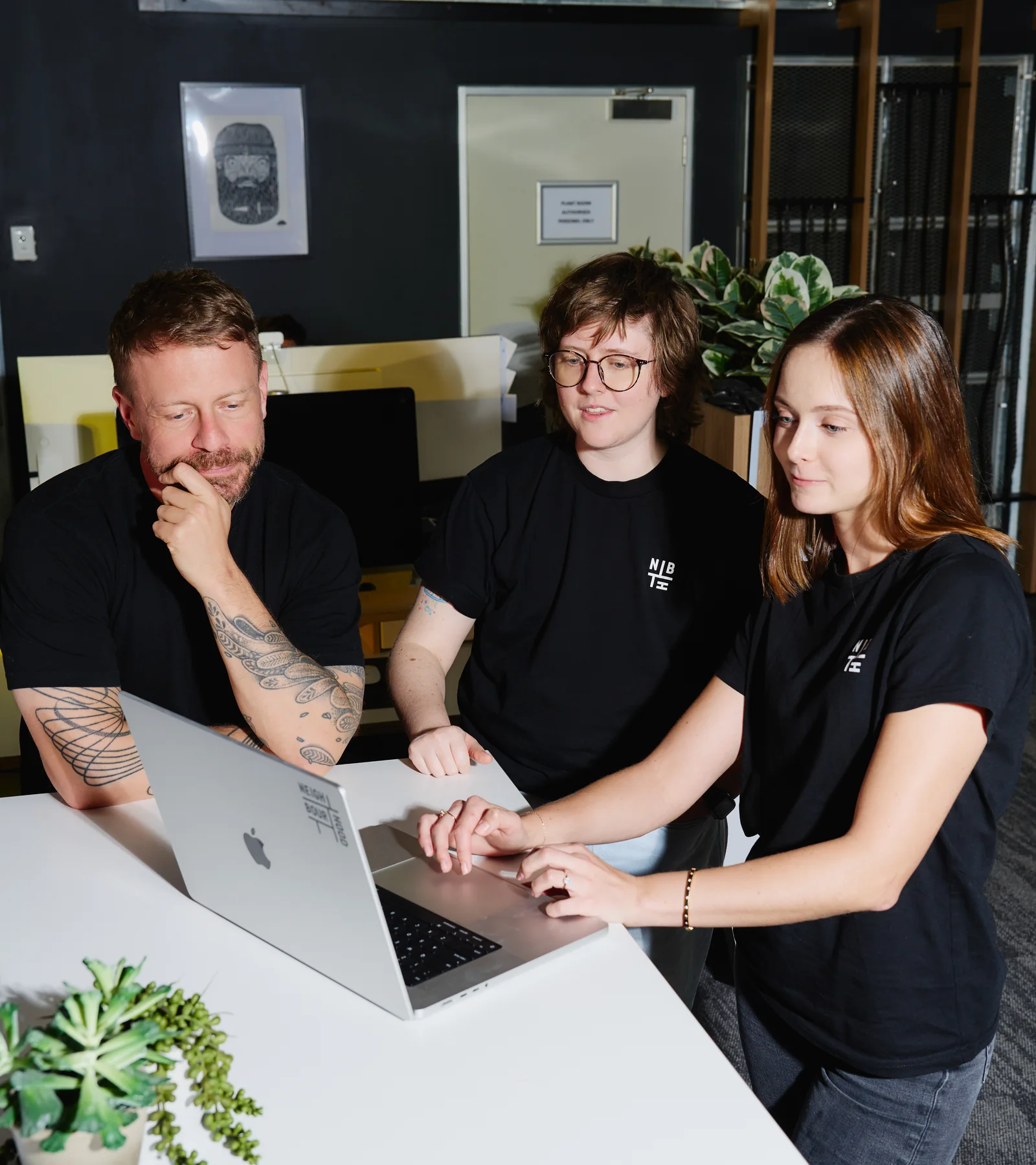 Three Neighbourhood team members around a laptop in the studio