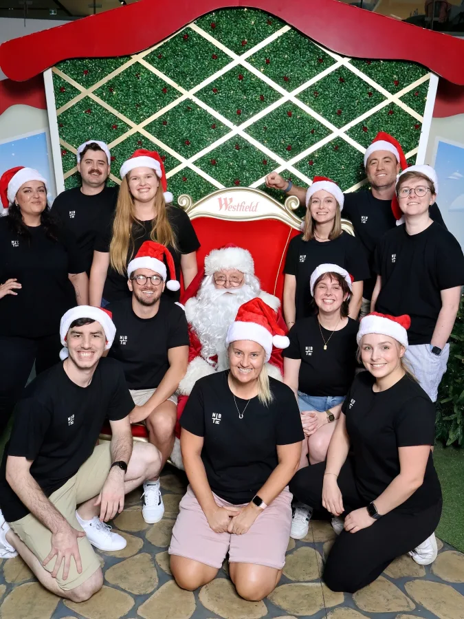 The crew in santa hats with Santa at Christmas