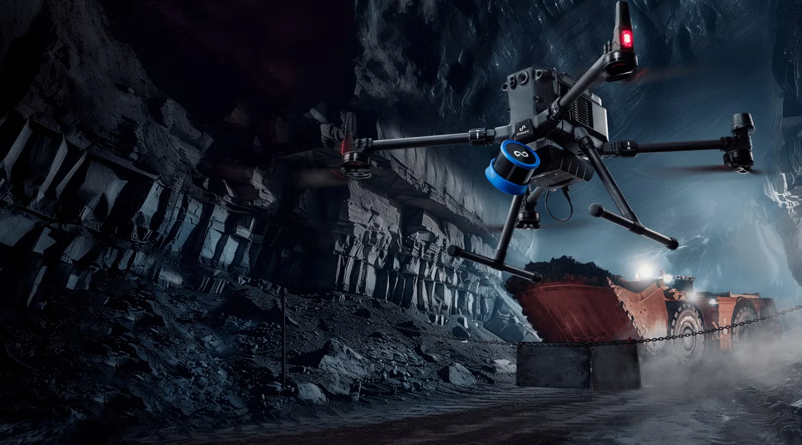 A drone carrying an Emesent LiDAR scanner through an underground mine, with a loader working behind it